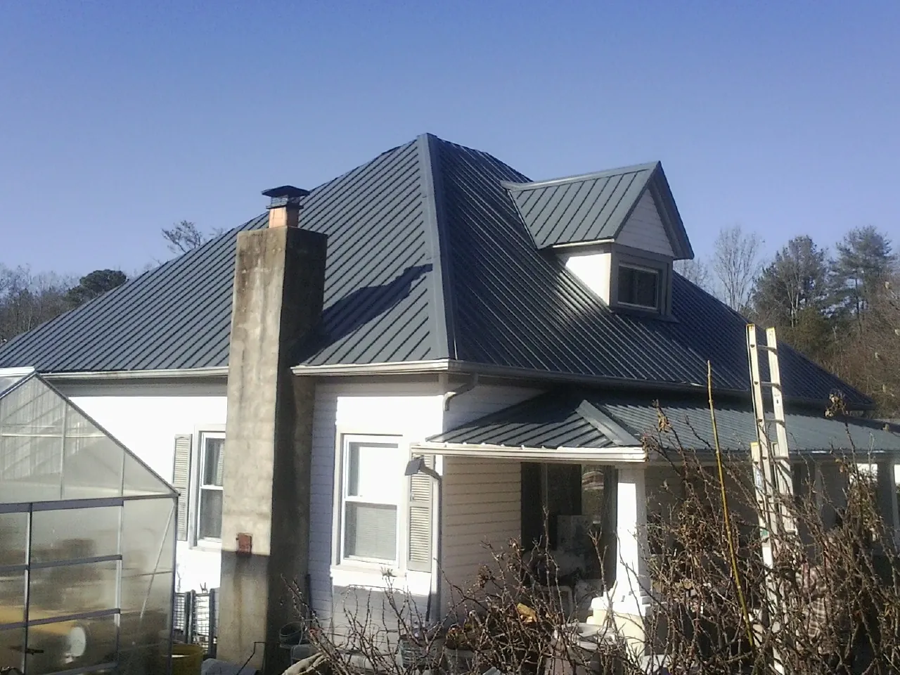 Dark blue standing seam metal roof on a white farmhouse with dormer — Slate & Tile Roof Repair by Roofing Brothers in North Conway