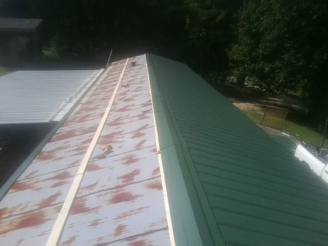 Old rusted panels beside newly installed green metal roofing — Wind Damage Roof Repair by Roofing Brothers in North Conway