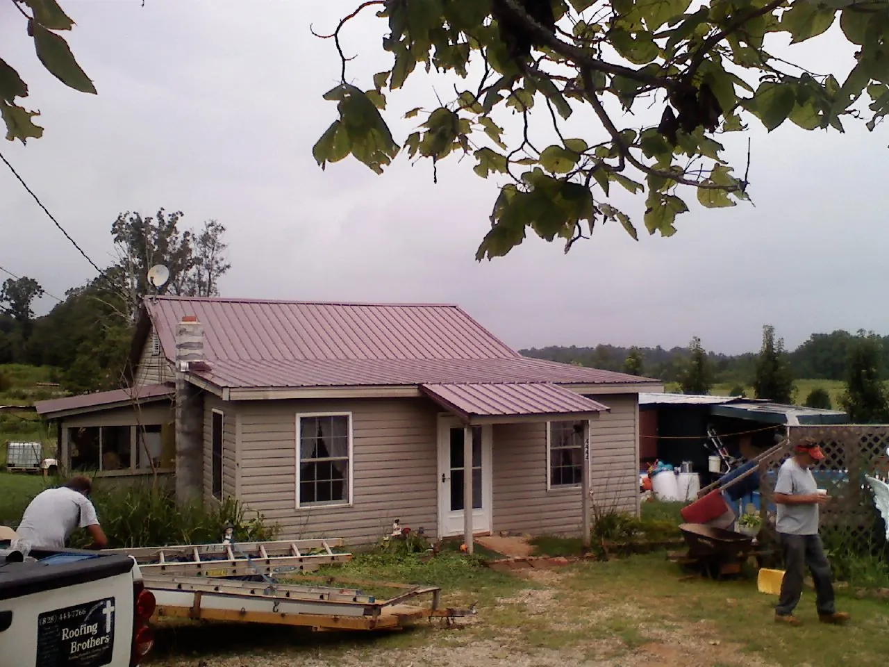 Crew finishing a mauve metal roof on a small farmhouse in North Conway