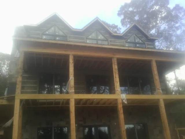 Dormers and porch framing on a large log home under construction — Roof Coating work by our crew in North Conway