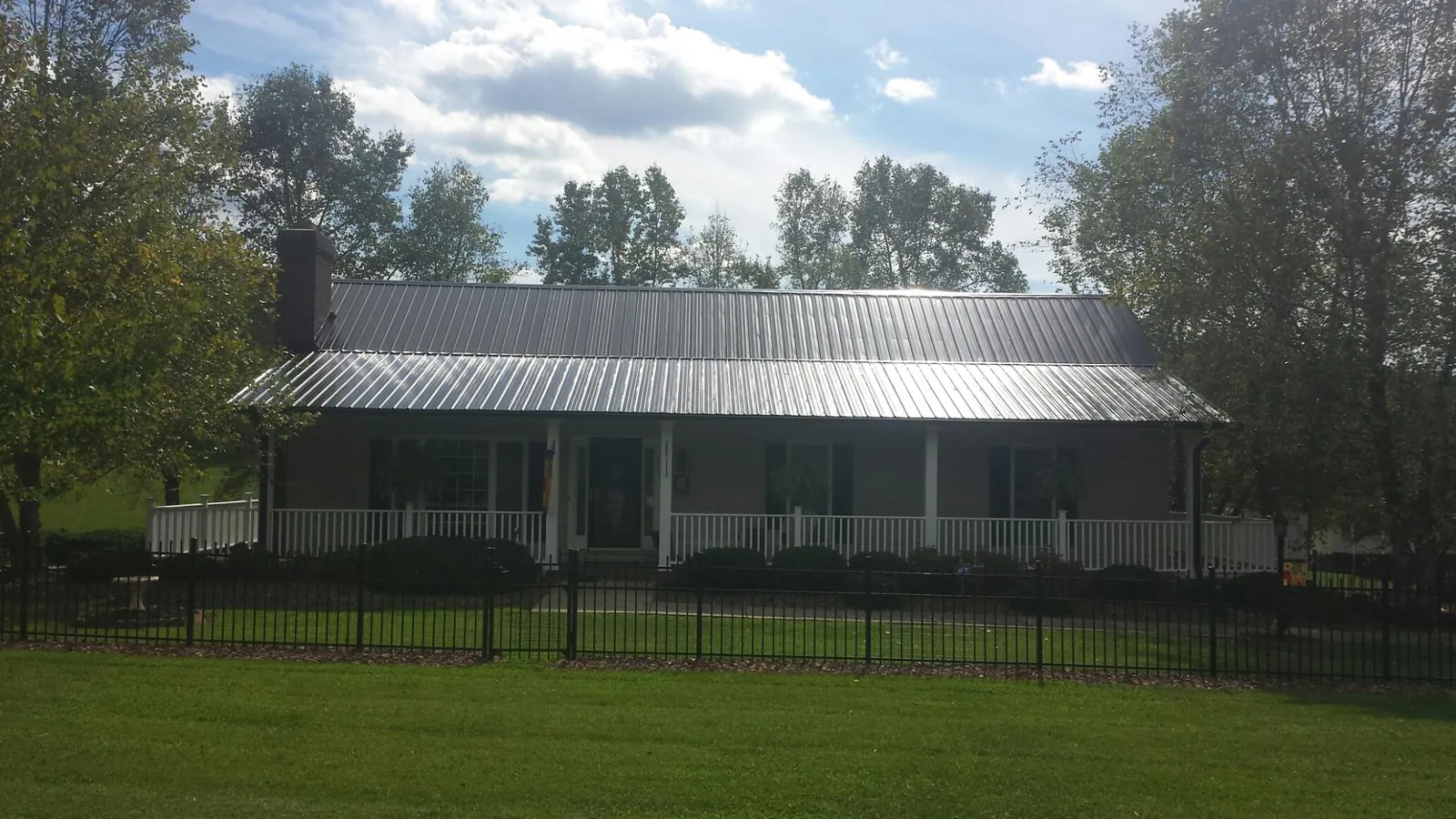 Gray metal roof on a brick ranch with a full width front porch — Gutter Guard Installation work by our crew in North Conway