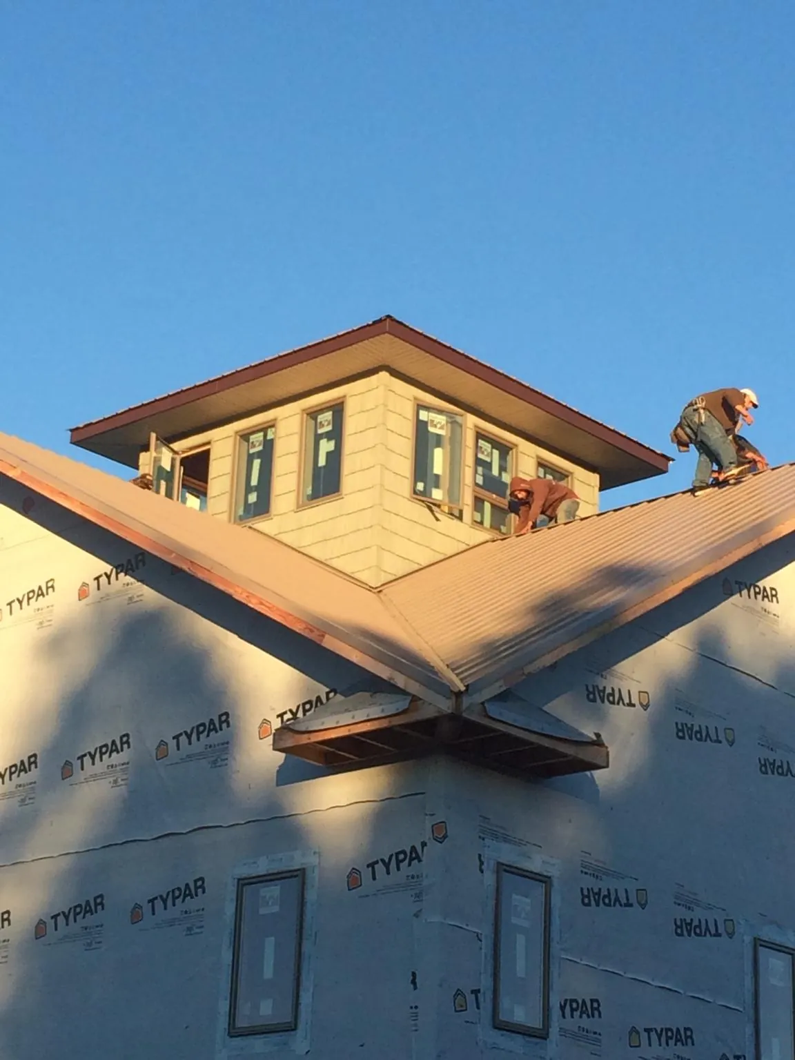 Roofers working around a rooftop cupola on a new metal roof at sunset — Roof Waterproofing in North Conway by Roofing Brothers